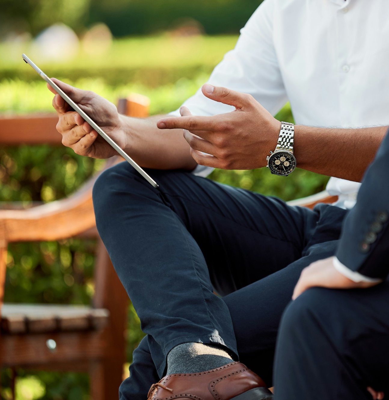 An outdoor consultation: one person showing another something on a tablet