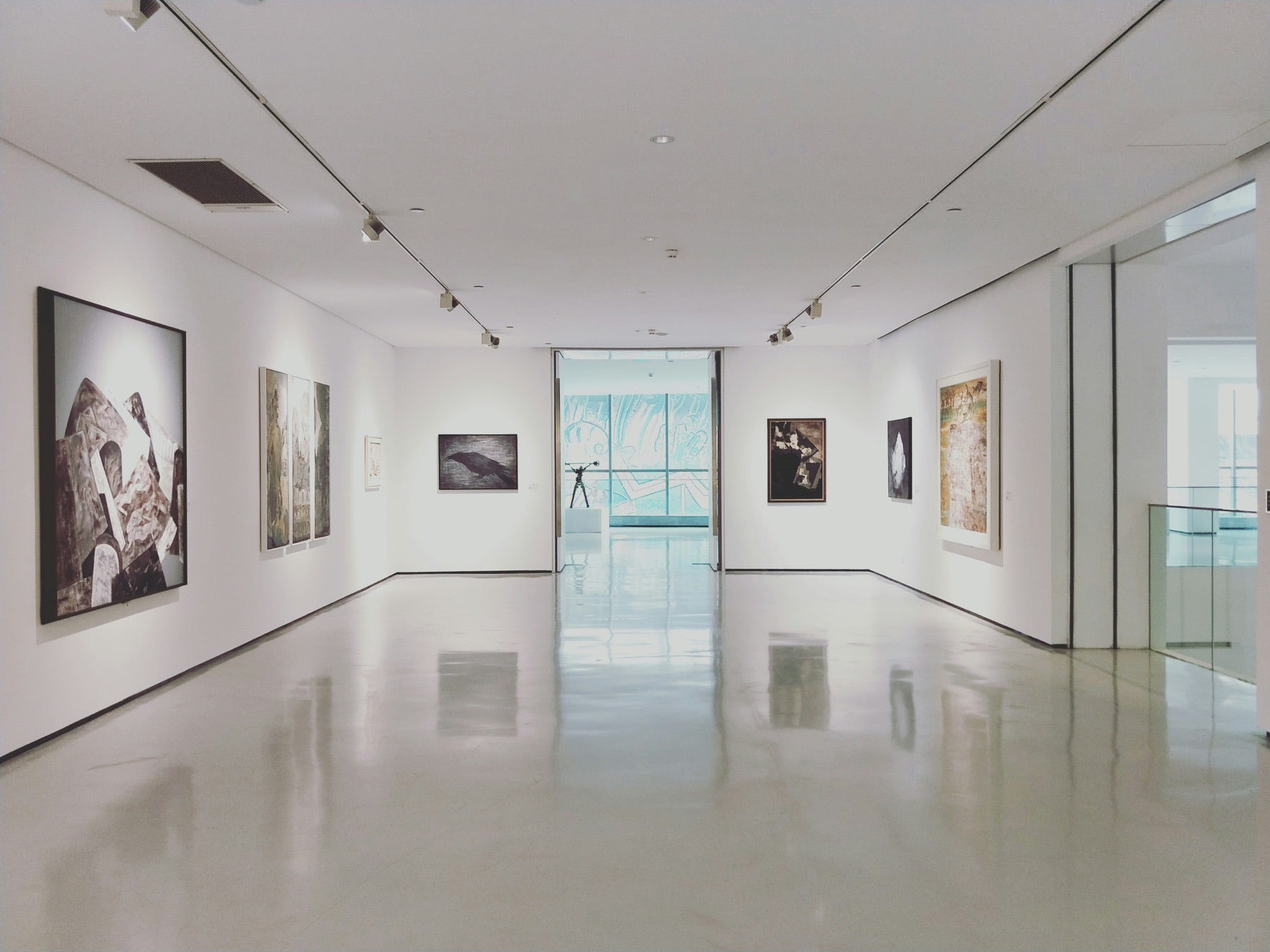 View into a bright gallery room with framed works on both walls